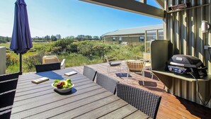 Eine Terrasse im Freien mit Grill, Sitzgelegenheit und Blick auf ein Gebäude im Hintergrund.