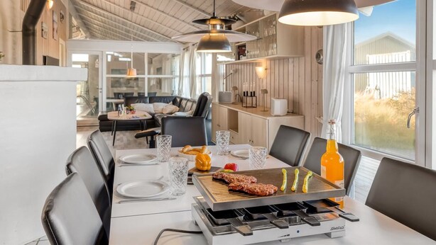 Eine moderne Küche mit Grill, Esstisch und Stühlen.