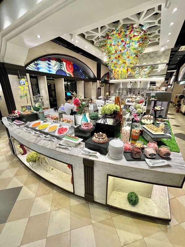 Un buffet proposant une variété de plats et agrémenté d’éléments décoratifs, le tout dans un cadre d’hôtel moderne.