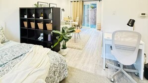 A modern bedroom with a bed, a desk, and a chair. There is a bookshelf and a potted plant. - Pet friendly private backyard Garden studio (Pickering)