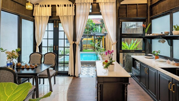 Una cocina moderna con comedor, ventanas amplias y vista a una piscina.