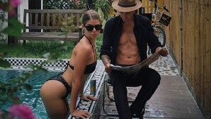 Un hombre y una mujer junto a una piscina, con una bicicleta y una cesta sujeta a ella.