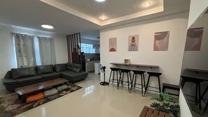 A modern living room with a sectional sofa, a coffee table, and a dining area with bar stools.