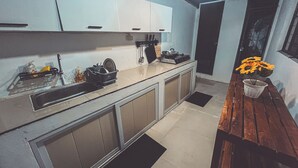 A modern kitchen with a sink, stove, and cabinets. There is a wooden bench and a potted plant on the right.
