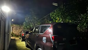 A maroon SUV parked in a narrow driveway at night.
