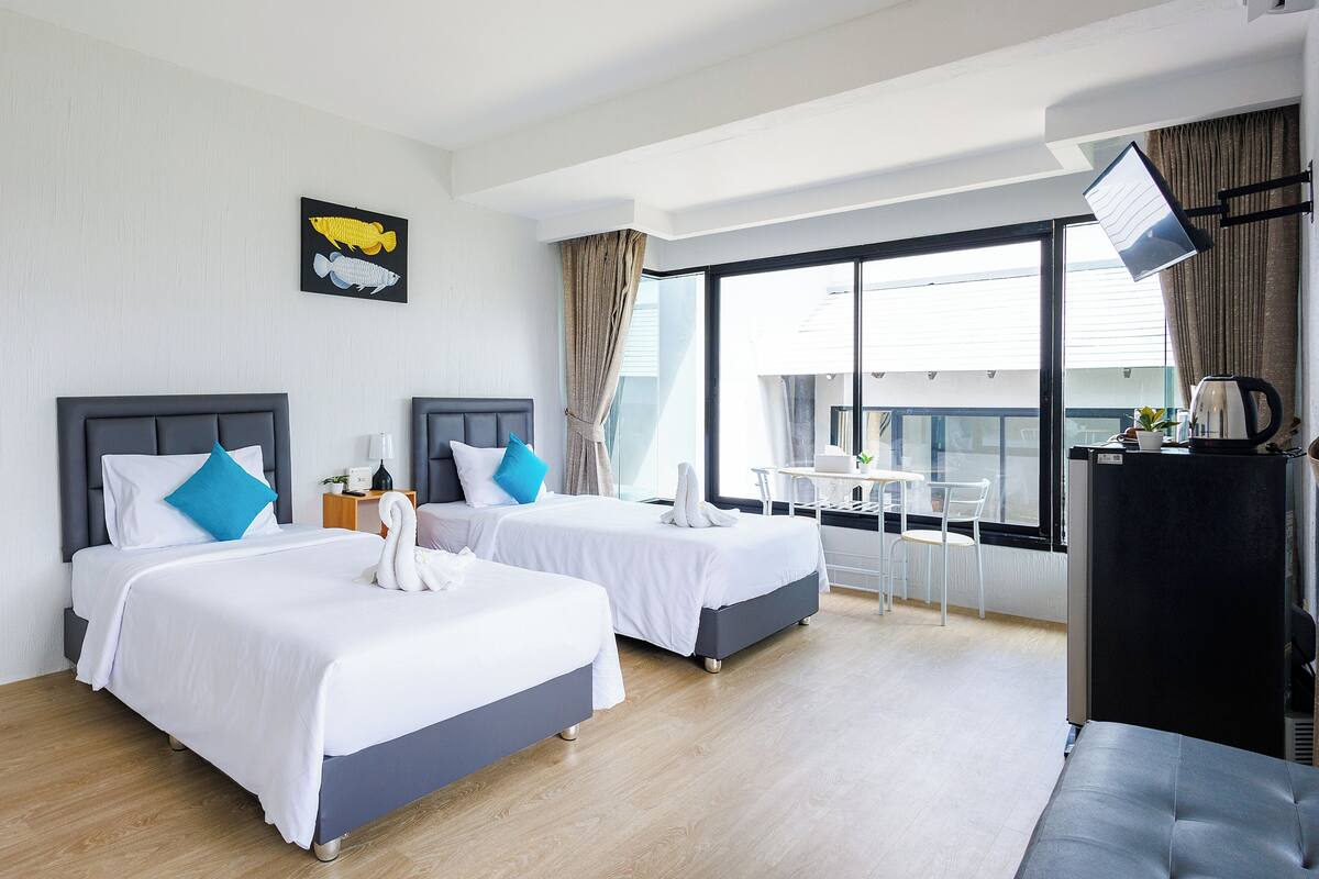 A hotel room with two beds, a dining table, and a kitchenette.