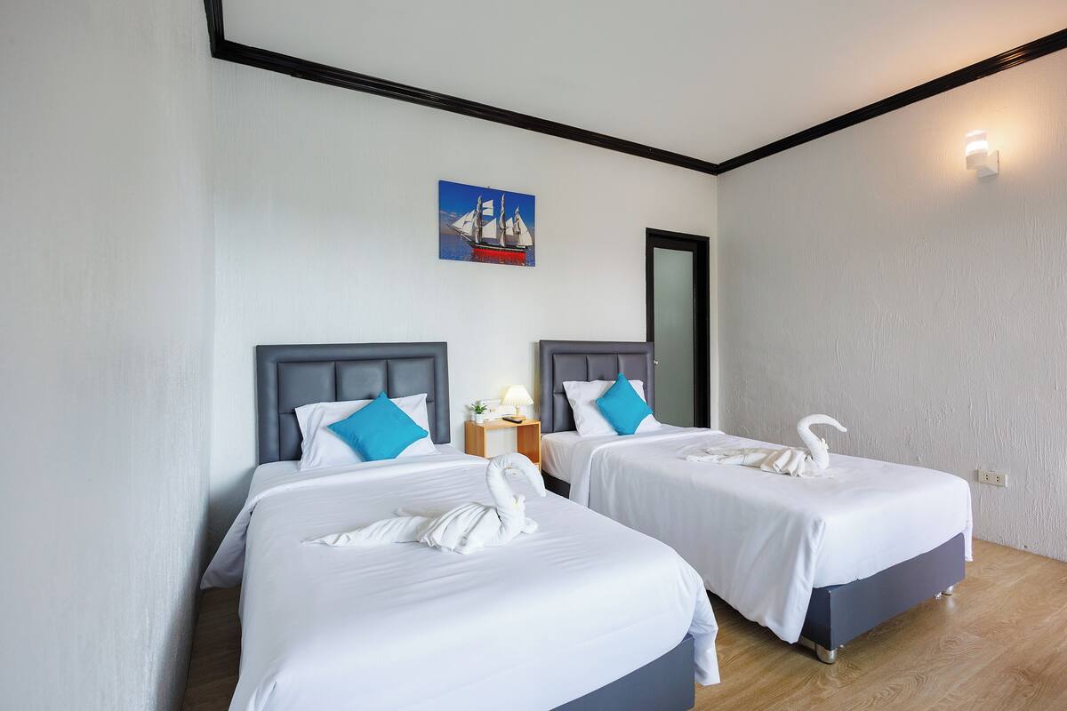 A hotel room with two beds, each with a headboard, a nightstand with a lamp, and a wall-mounted painting.