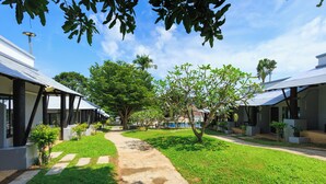 A pathway leading to a row of modern buildings with a clear sky and lush greenery. - Peace Garden Resort Koh Samui (Koh Samui)
