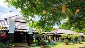 A traditional building with a tiled roof, surrounded by a garden with potted plants and a paved walkway. - Peace Garden Resort Koh Samui (Koh Samui)