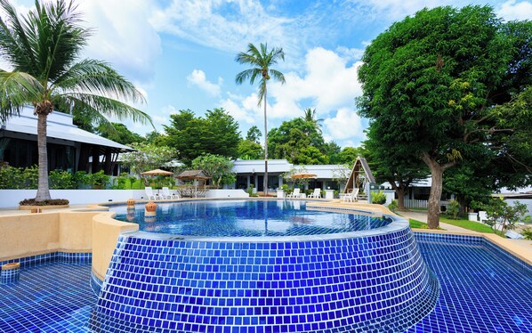 A swimming pool with blue mosaic tiles, surrounded by palm trees and a white building with a covered seating area. - Peace Garden Resort Koh Samui (Koh Samui)