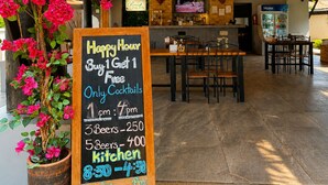 A restaurant with a chalkboard sign offering happy hour deals, a bar area, and a seating space. - Peace Garden Resort Koh Samui (Koh Samui)