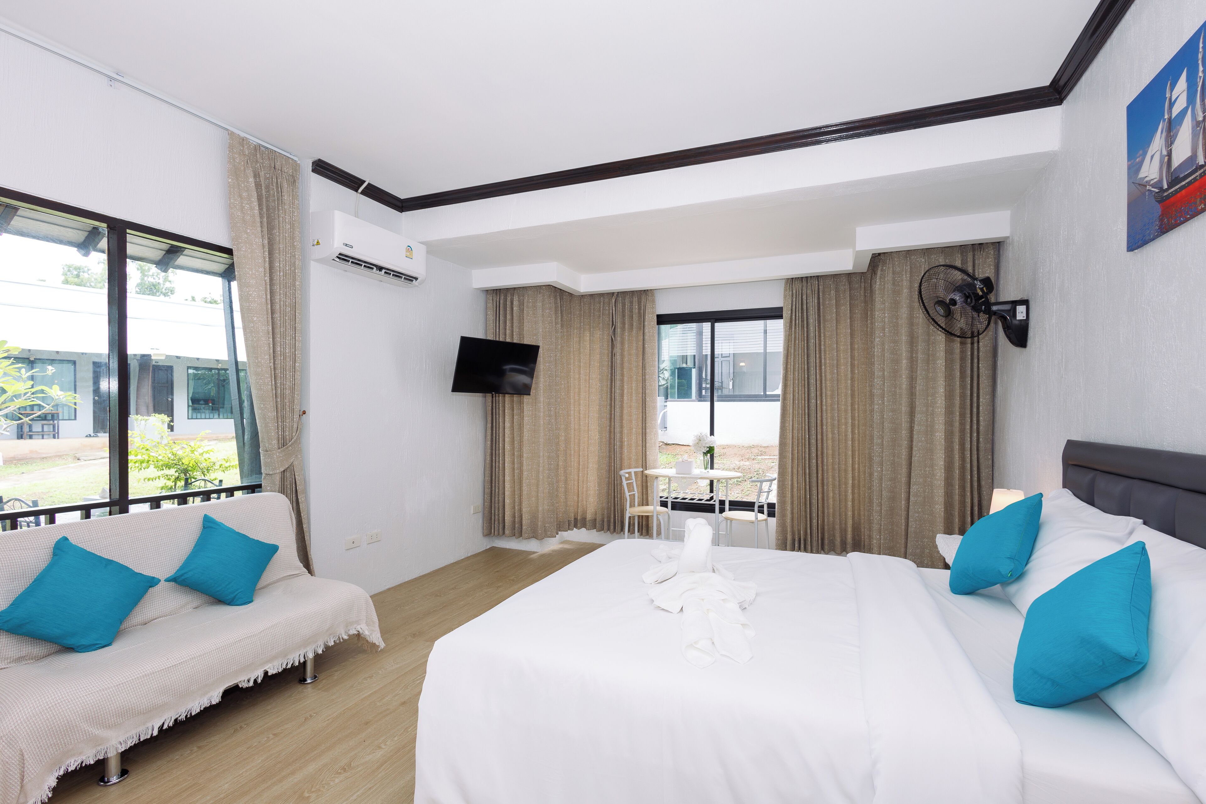 Habitación de hotel con cama, sofá, televisión y ventana con cortinas.