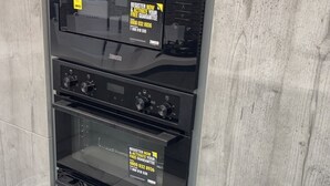 Horno industrial con panel de control digital y puerta de vidrio, instalado en una cocina con salpicadero de mármol gris.