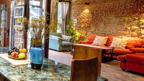 A cozy living area with a red sofa, a blue vase with dried flowers, and a stone wall. - La Rocca An Bang beach (Da Nang)