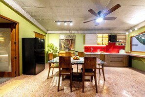A compact kitchen with a dining area, a ceiling fan, and a refrigerator. - La Rocca An Bang beach (Da Nang)