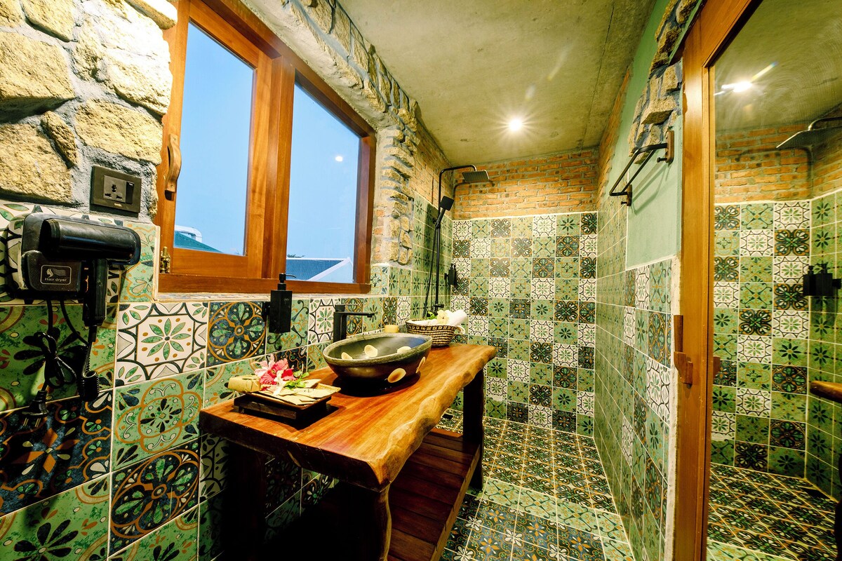 Casa de banho com parede de pedra, uma janela e chão em azulejo.