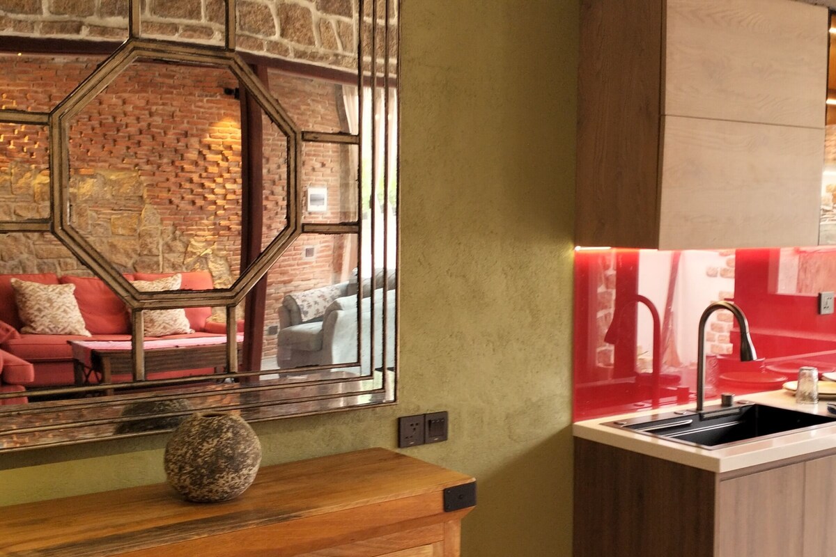 Uma cozinha moderna com forno embutido, pia e painel de fundo vermelho.