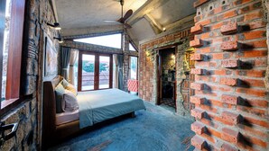 A bedroom with a large bed, stone walls, and a brick wall. - La Rocca An Bang beach (Da Nang)