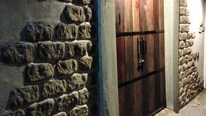 A stone-walled building with a wooden door and a small illuminated sign above it. - La Rocca An Bang beach (Da Nang)