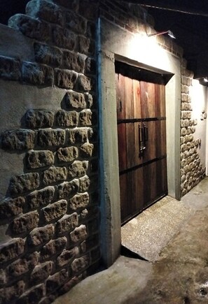 A stone-walled building with a wooden door and a small illuminated sign above it. - La Rocca An Bang beach (Da Nang)