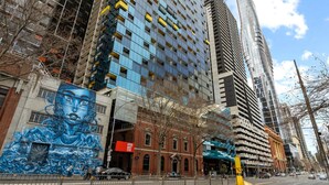 A modern urban street with tall buildings, a mural on a brick building, and a clear sky. - Cozy Studio Near Southern Cross with City Views (Melbourne)