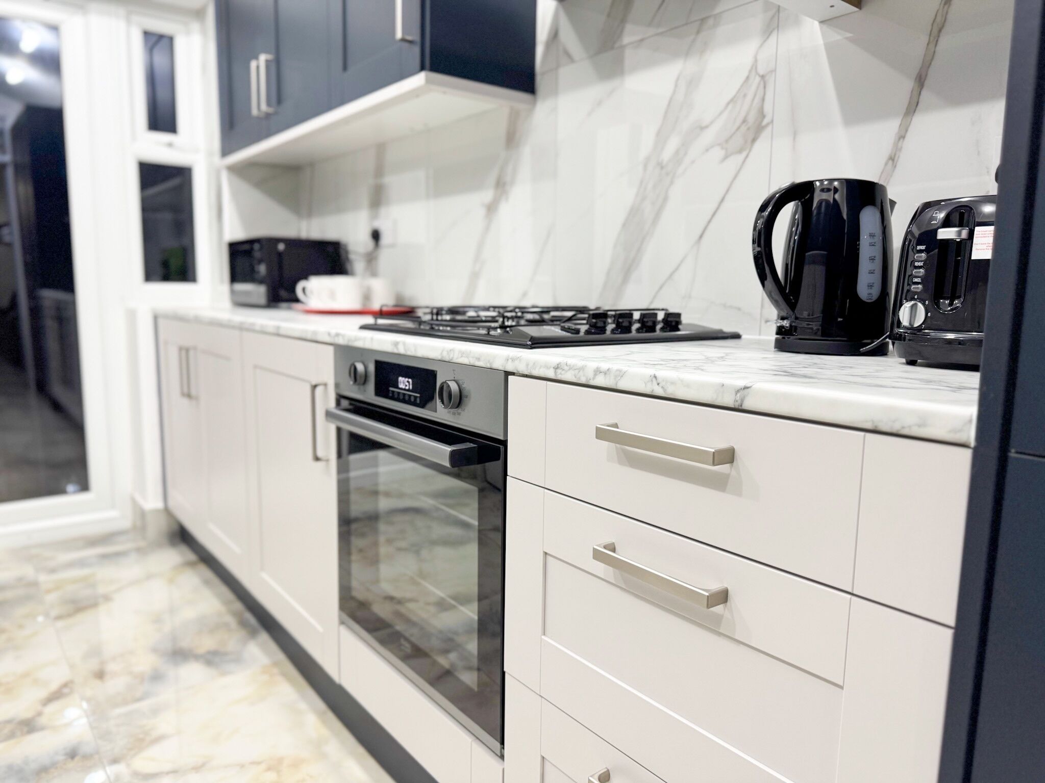 Cozinha moderna com forno embutido, fogão a gás e máquina de café.