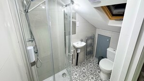 A compact bathroom with a glass shower enclosure, a white sink, and a toilet. - Modern North London Retreat - 7 Bedrooms (London)