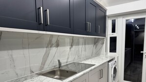 A modern kitchen with marble countertops, a stainless steel sink, and a built-in washing machine. - Modern North London Retreat - 7 Bedrooms (London)
