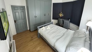 A bedroom with a bed, a wardrobe, a desk, and a window with curtains. - Modern North London Retreat - 7 Bedrooms (London)