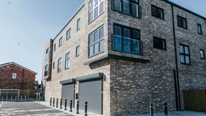 Ein mehrstöckiges Gebäude mit großen Fenstern, einer Ziegel-Fassade und einem Parkplatz mit Schutzpfosten.
