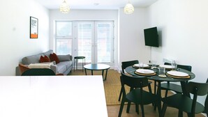 Ein modernes Wohnzimmer mit einer Couch, einem Couchtisch und einem Esstisch für vier Personen.