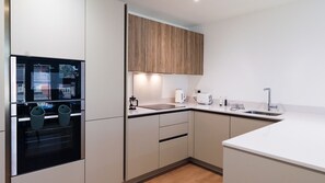 Una cocina moderna con horno integrado, cafetera, hervidor y pileta.