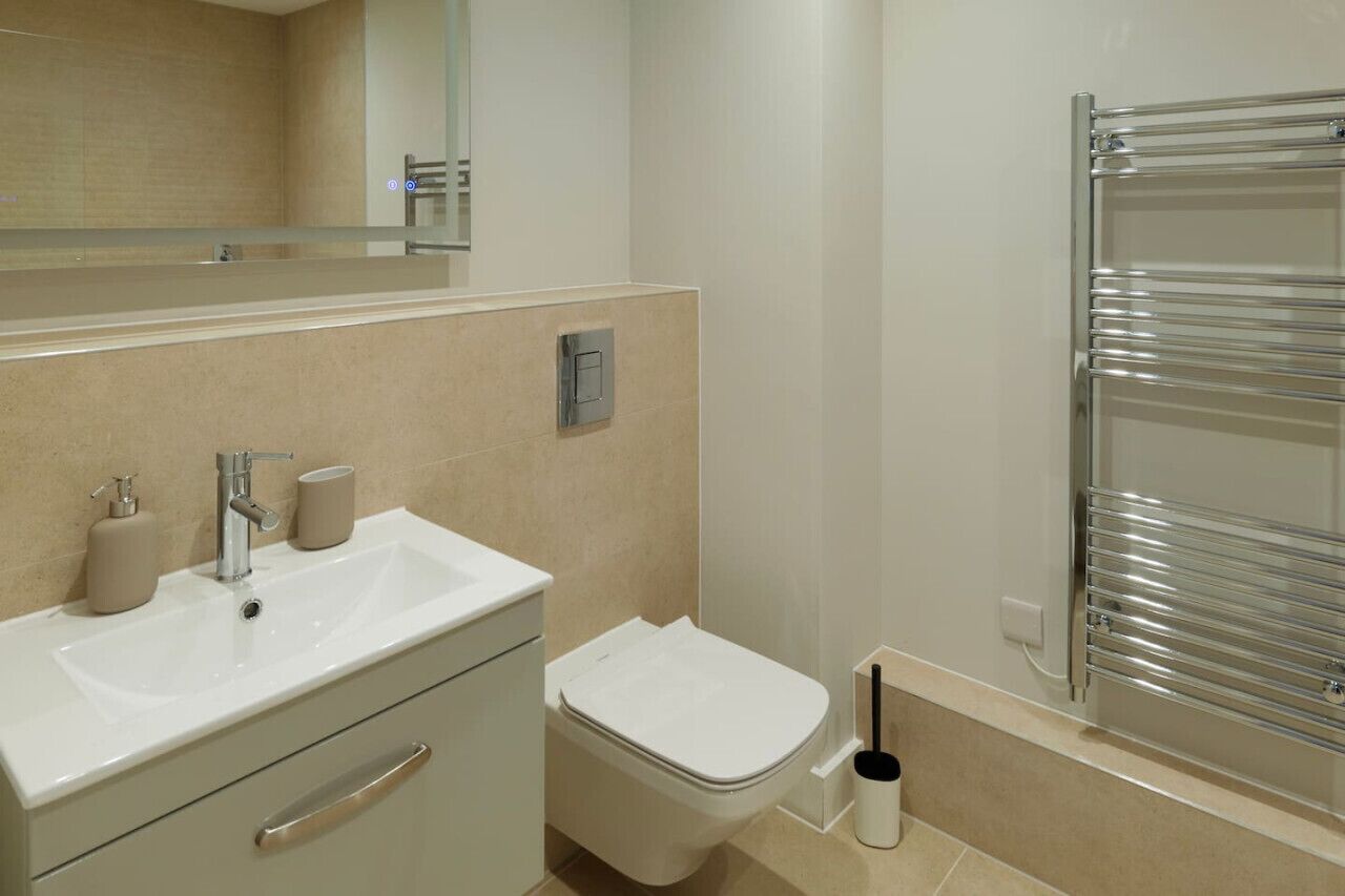 A bathroom with a white sink, a toilet, a mirror, and a towel rack.