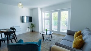 A modern living room with a sofa, chairs, a TV, and a large window.