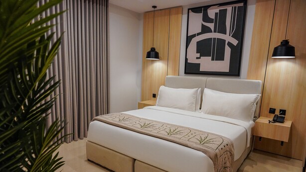 Een moderne slaapkamer met een groot bed, nachtkastjes en een wanddecoratie.