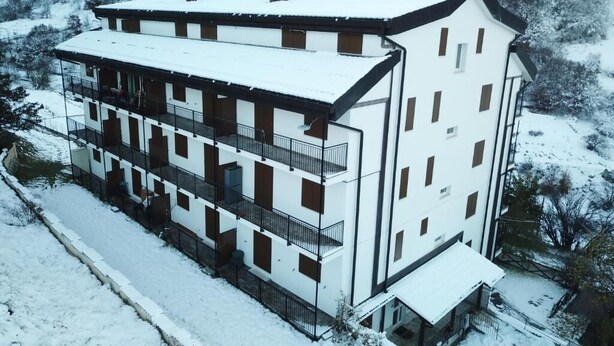 Ein mehrstöckiges Gebäude mit Balkonen, eingebettet in eine verschneite Landschaft.