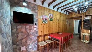 Ein Essbereich mit Steinwand, Holzvertäfelung, Fernseher und einer Chandelüstere.