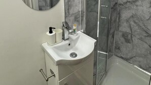 Een badkamer met een wit wastafel, een spiegel en een douche.