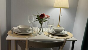 Een eettafel gedekt met borden, kommen, glazen en een vaas met bloemen.