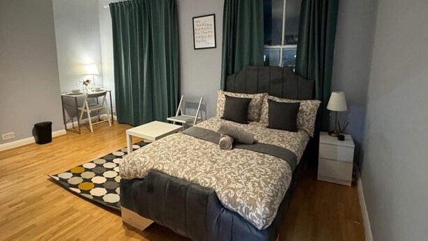 Een moderne slaapkamer met een bed, bureau en stoel.