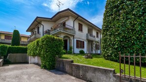 Une maison à deux étages avec un balcon, une allée en béton et un jardin bien entretenu.