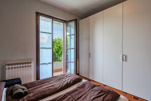 A bedroom with a bed, a radiator, and a sliding glass door leading to a balcony.