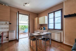 A compact kitchen with a dining area, a sliding glass door to an outdoor patio, and a view of greenery.