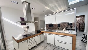 A modern kitchen with white cabinets, a stainless steel range hood, and a built-in oven. - Magnificent 158m² loft in Caluire le bas, 10mm from Lyon 6,  (Caluire-et-Cuire)