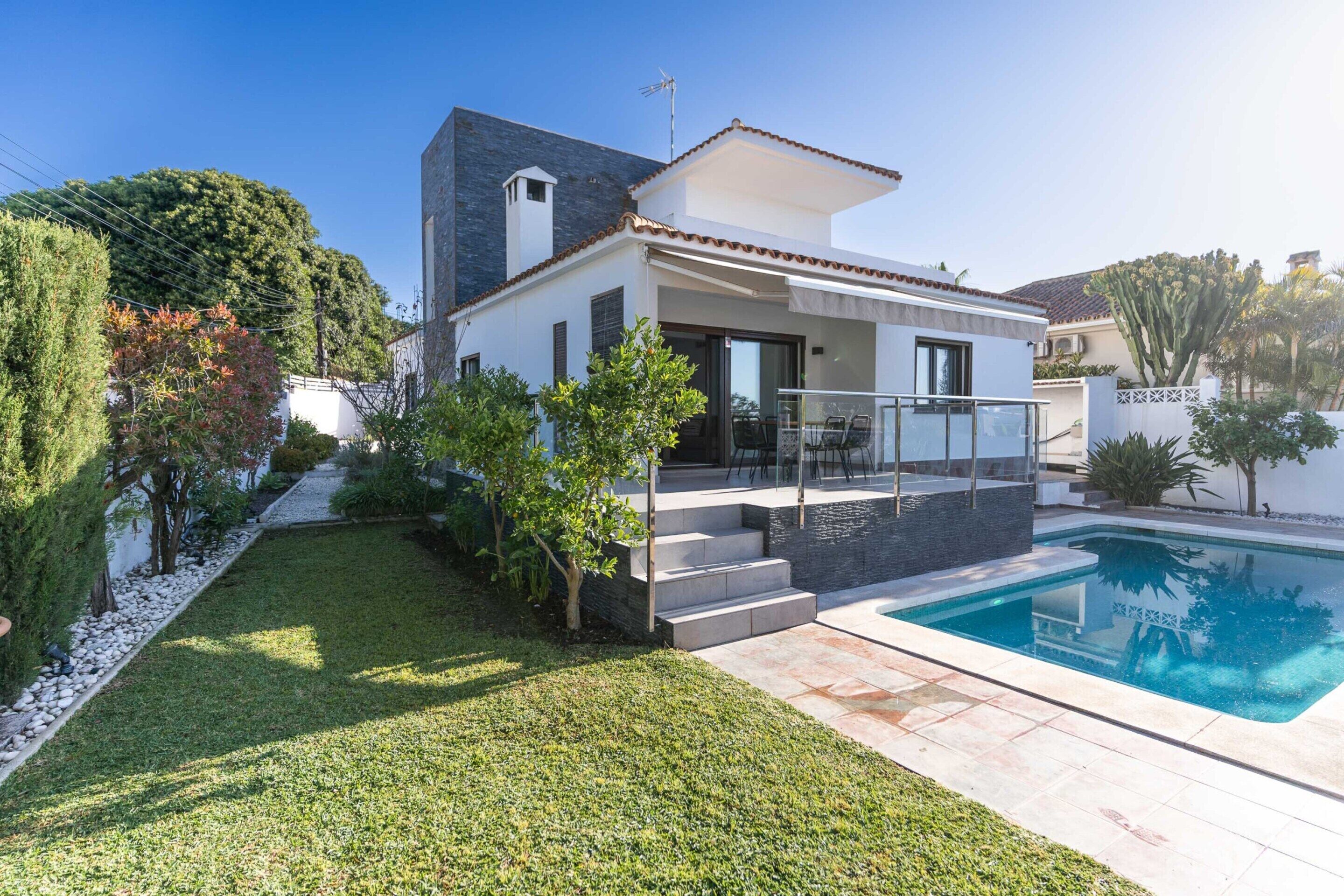 A modern house with a swimming pool, a covered patio, and a well-maintained garden.