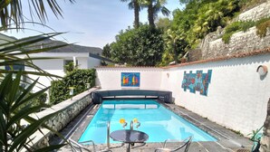 A swimming pool with a tiled deck, surrounded by a white wall with colorful murals.