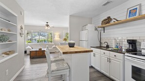 Una cocina moderna con armarios blancos, una isla de madera y una cafetera.