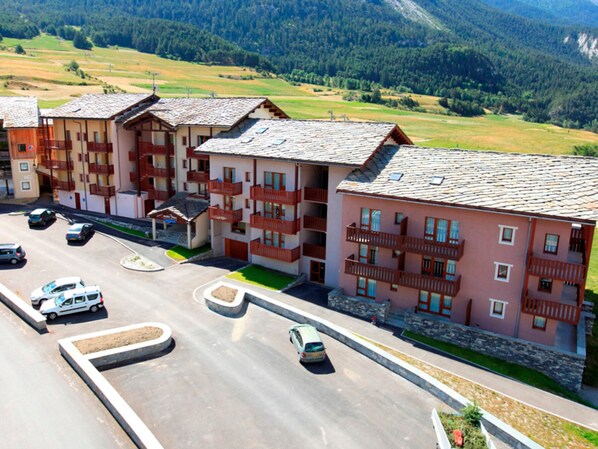Un hôtel à plusieurs étages doté de balcons, d’un parking et situé dans un cadre montagneux.