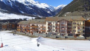 A hotel with multiple floors, balconies, and a ski lift in the foreground.