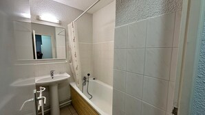 A bathroom with a sink, mirror, and bathtub.